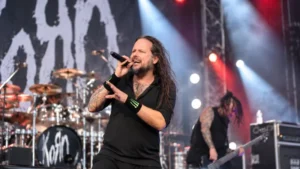 Korn performing live on stage during a UK concert with dramatic red and white lighting